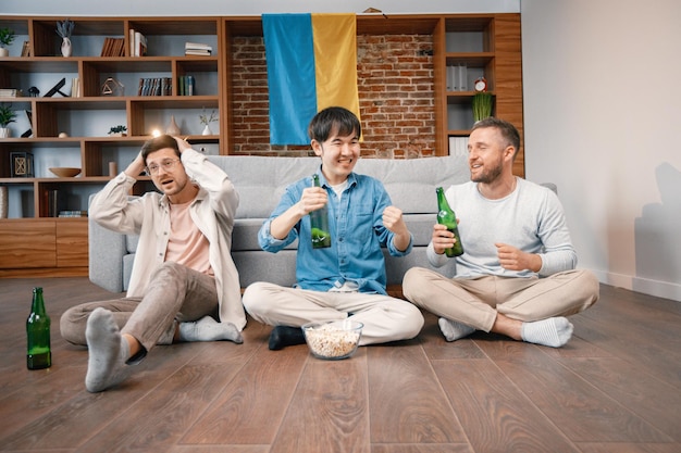 Drei Männer schauen sich im Fernsehen ein Fußballspiel an und trinken ein Bier