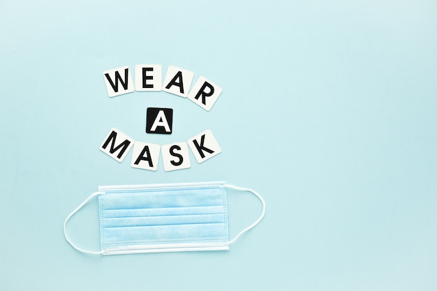 Drei medizinische Masken und eine Textnachricht tragen eine Maske auf hellblauem Hintergrund Poster-Banner-Virus