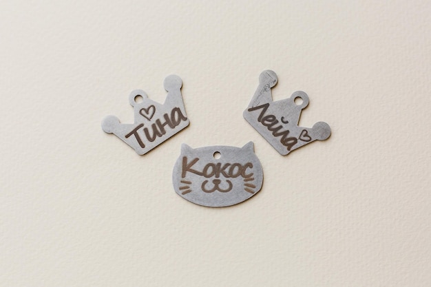 Foto drei metallmarken in katzenform mit den namen tula und neko darauf.