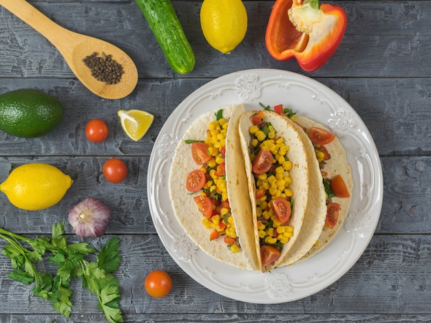 Drei mexikanische Tacos auf einem Teller mit Zutaten zum Kochen