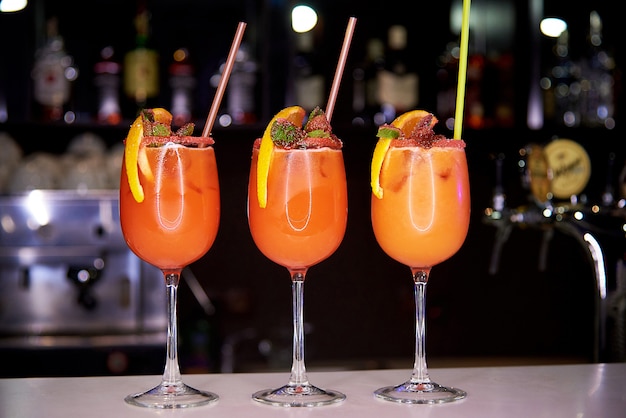 Drei orange kalte cocktails verziert mit zuckerkrumen