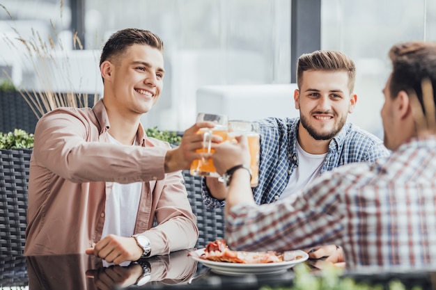 Drei Personen Langhaus schönen Tag, sie jubeln im Café auf der Sommerterrasse mit Bier