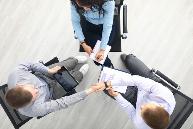 Drei Personen sitzen auf einem Stuhl in der Kreisansicht und besprechen die Arbeit.