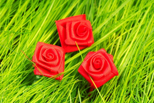 Drei Rosen aus Textilien auf einem Hintergrund aus grünem Gras