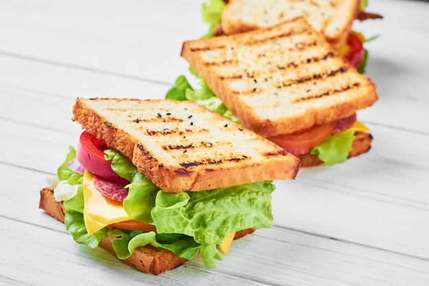 Drei Sandwiche mit Schinken, Kopfsalat und Frischgemüse auf einem weißen Hintergrund