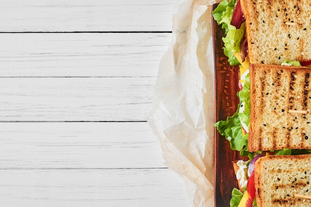 Drei Sandwiche mit Schinken, Kopfsalat und Frischgemüse auf einem weißen Hintergrund