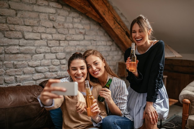 Drei schöne Freundinnen machen ein Selfie in der Wohnung