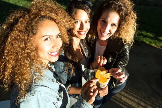 Drei schöne junge Frauen besuchen Markt auf der Straße.