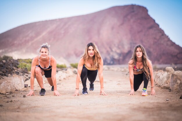 Drei schöne junge Läuferinnen, die bereit sind, für hartes Training und Fitness-Outdoor-Aktivitäten zu starten und zu laufen