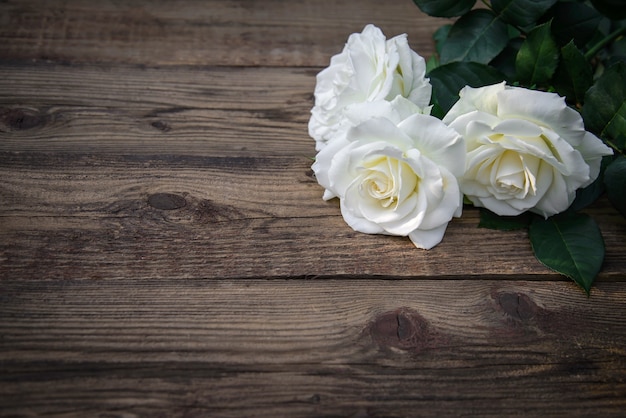 Drei schöne weiße Rosen auf einem rustikalen hölzernen Hintergrund, Kopienraum