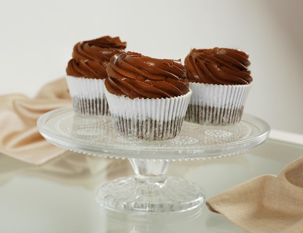 Drei Schokoladen-Cupcakes auf hellem Glashintergrund hautnah