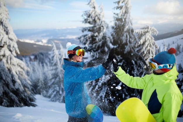 Drei Snowboarder, die an Skigebietsfreunden spazieren gehen, die mit ihren Snowboards auf die Bergspitze klettern