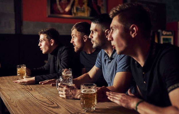 Drei Sportfans in einer Bar beim Fußball gucken