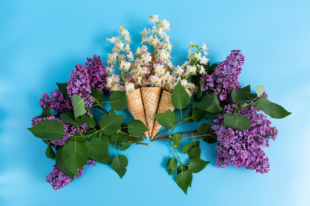 Drei süße knusprige Waffelbecher mit Kastanienblüten auf blauem Grund