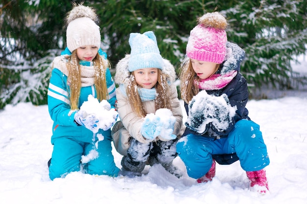 Drei süße Mädchen machen zusammen Schneebälle