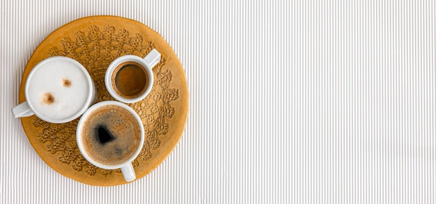 Drei Tassen Kaffee auf einem weißen Texturhintergrund flach gelegt