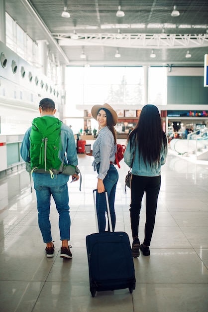 Drei Touristen mit Gepäck im Flughafen, Rückansicht. Passagiere mit Gepäck im Flugterminal