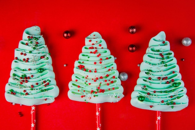 Drei türkisfarbene Weihnachtsbäume aus Bizet auf Stöcken mit bunten Pulverbällchen übersät auf heller...