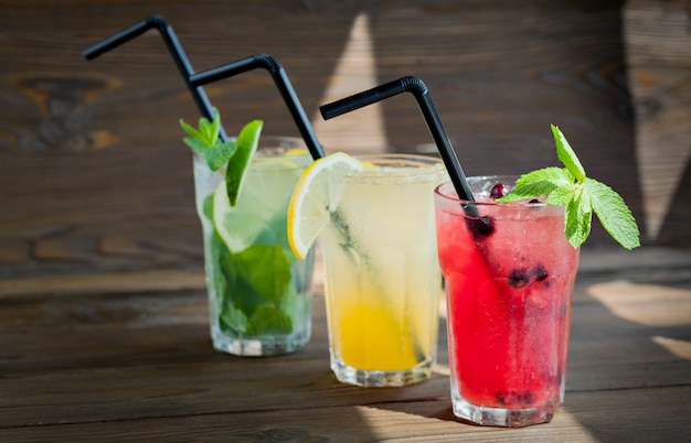 Foto drei verschiedene erfrischende limonade mit zitrone und limette auf einem holztisch. sommergetränk