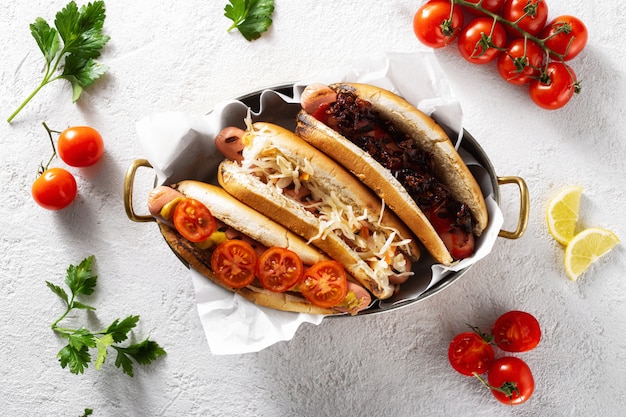 Drei verschiedene Hot-Dog-Grills in einer Pfanne auf hellem Hintergrund, Draufsicht