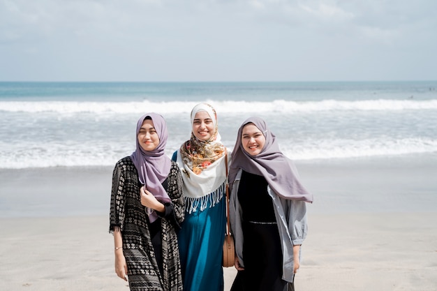 Drei verschleierte Frauen genießen einen Urlaub am Strand