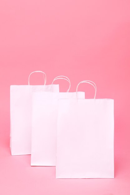 Drei weiße Papiertüten auf Pink