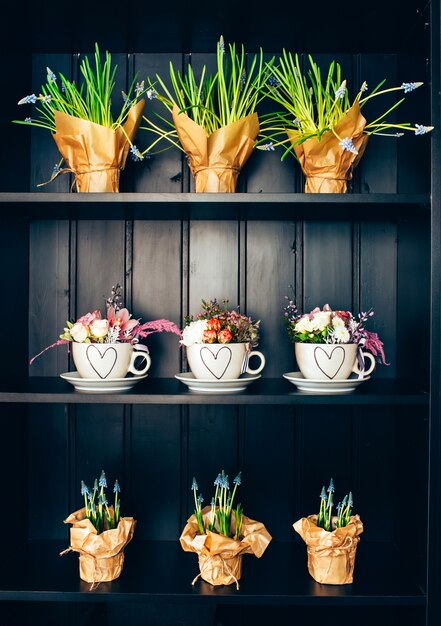 Drei weiße Tassen mit Blumen im Regal.