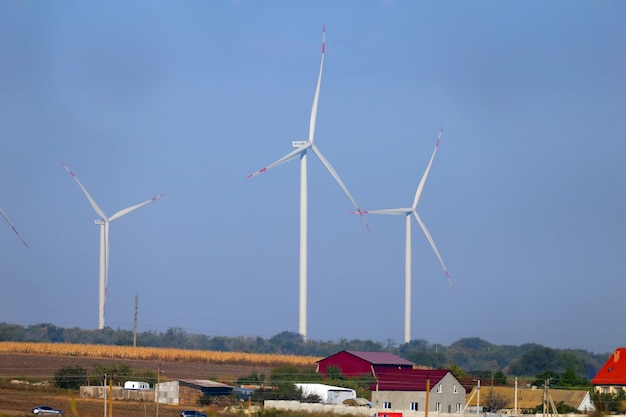 Drei Windkraftanlagen werden in der Ferne vor blauem Himmel aus einem ungewöhnlichen Winkel geschossen.