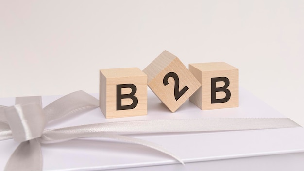 Drei Würfel mit Text b2b auf der weißen Oberfläche einer Geschenkbox, die mit einem leichten festlichen Band gebunden ist