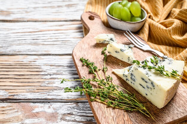 Dreieck Blauschimmelkäse mit Trauben. Weißer hölzerner Hintergrund. Draufsicht. Speicherplatz kopieren