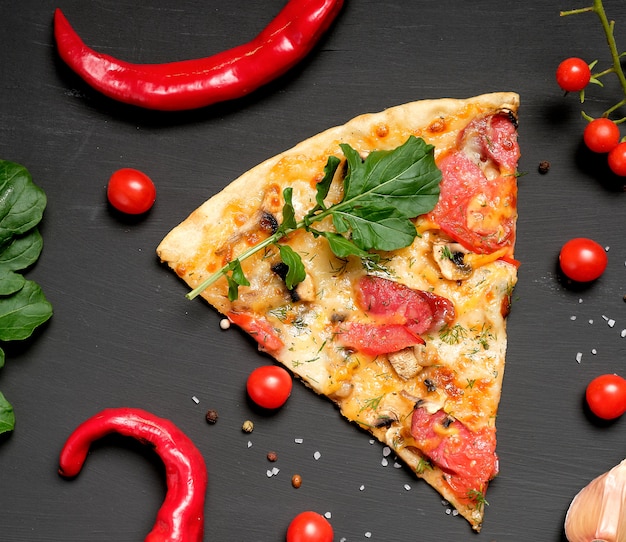 Dreieckiges Stück gebackene Pizza mit Pilzen, geräucherten Würsten, Tomaten und Käse