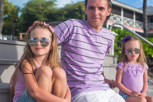 Dreiköpfige Familie, die auf dem hölzernen Dock genießt Meerblick sitzt