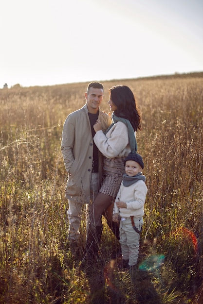 Dreiköpfige Familie mit einem Jungen Kind Mama und Papa stehen im Herbst bei Sonnenuntergang auf einem Feld