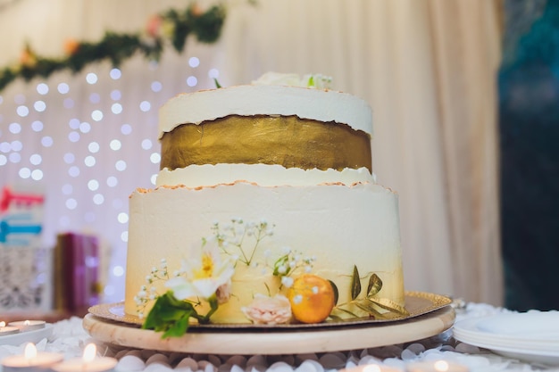 Foto dreistöckiger weißer hochzeitskuchen mit blumen aus mastik auf einem weißen holztisch bild für ein menü oder einen süßwarenkatalog mit kopierplatz