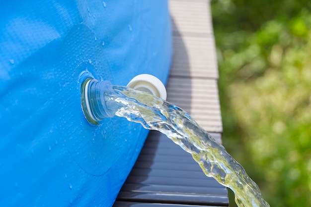 Drenaje de agua de una piscina inflable al aire libre. concepto de cuidado de piscina inflable.