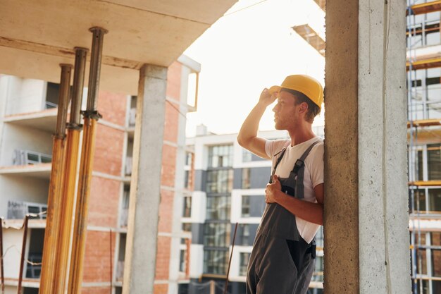 Drinnen ausruhen Junger Mann, der tagsüber in Uniform auf dem Bau arbeitet