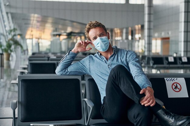 Drinnen sitzen Junger Mann in formeller Kleidung befindet sich auf einem modernen Flughafen Konzept des Urlaubs