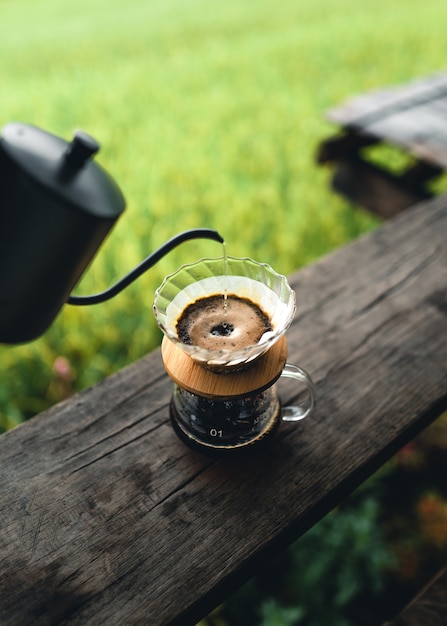 Drip-Kaffeemaschine im Freien auf Holztisch-Reisfeld-Hintergrund