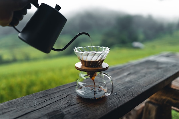 Drip-Kaffeemaschine im Freien auf Holztisch-Reisfeld-Hintergrund