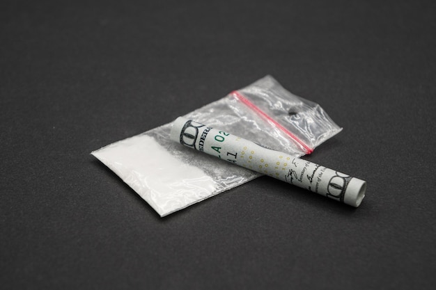 Drogenabhängigkeit. Ein Drogenpaket und hundert Dollar. Ein aufgerollter Dollar.