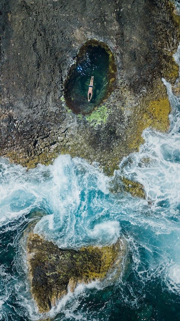 Drohnenansicht eines Mannes, der im Gezeitenbecken schwimmt