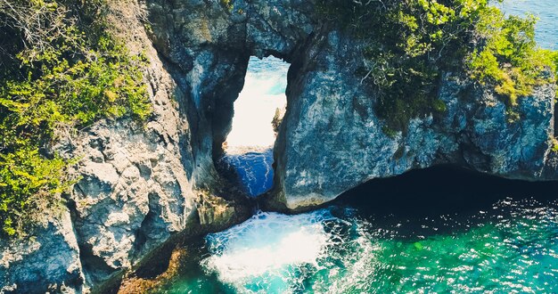 Drohnenblickozean mit Wellen, die die Felsen an der Küste treffen