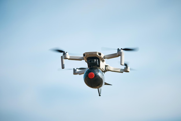 Dron civil de consumo con una gran bomba a bordo vuela en el cielo azul