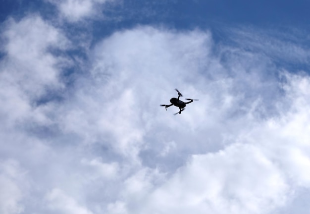 Dron de contorno con cámara volando en el cielo con nubes en un día soleado vista de abajo hacia arriba