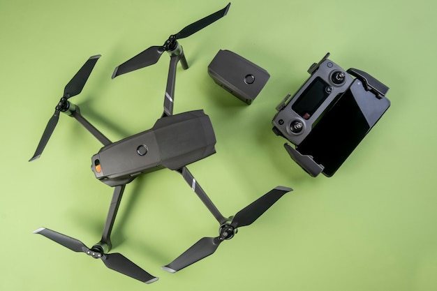 Un dron, su controlador y un teléfono inteligente en una superficie verde vista desde arriba.