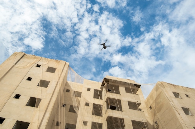 Un dron volando junto a un edificio en construcción.