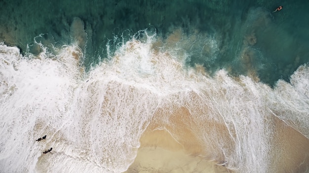 Drone aéreo atirou em enormes ondas da praia do oceano, areia amarela e paisagem de água azul e verde cristalina em