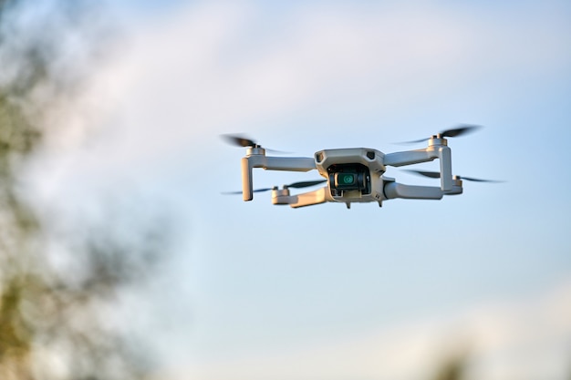 Drone cuadricóptero en el cielo. Pequeño avión no tripulado vuela en el cielo tomando videos y fotos. Entrega de aire a control remoto y espía.