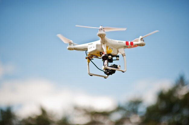 Drone quad copter con cámara digital de alta resolución volando en el cielo azul