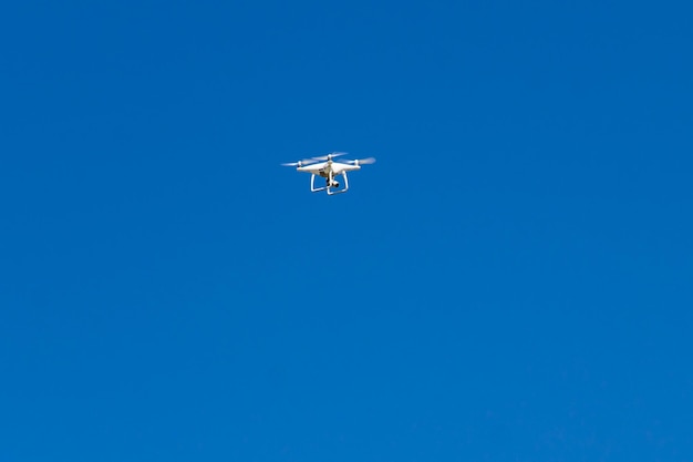 Drone Quadcopter con la cámara flotando en el cielo azul